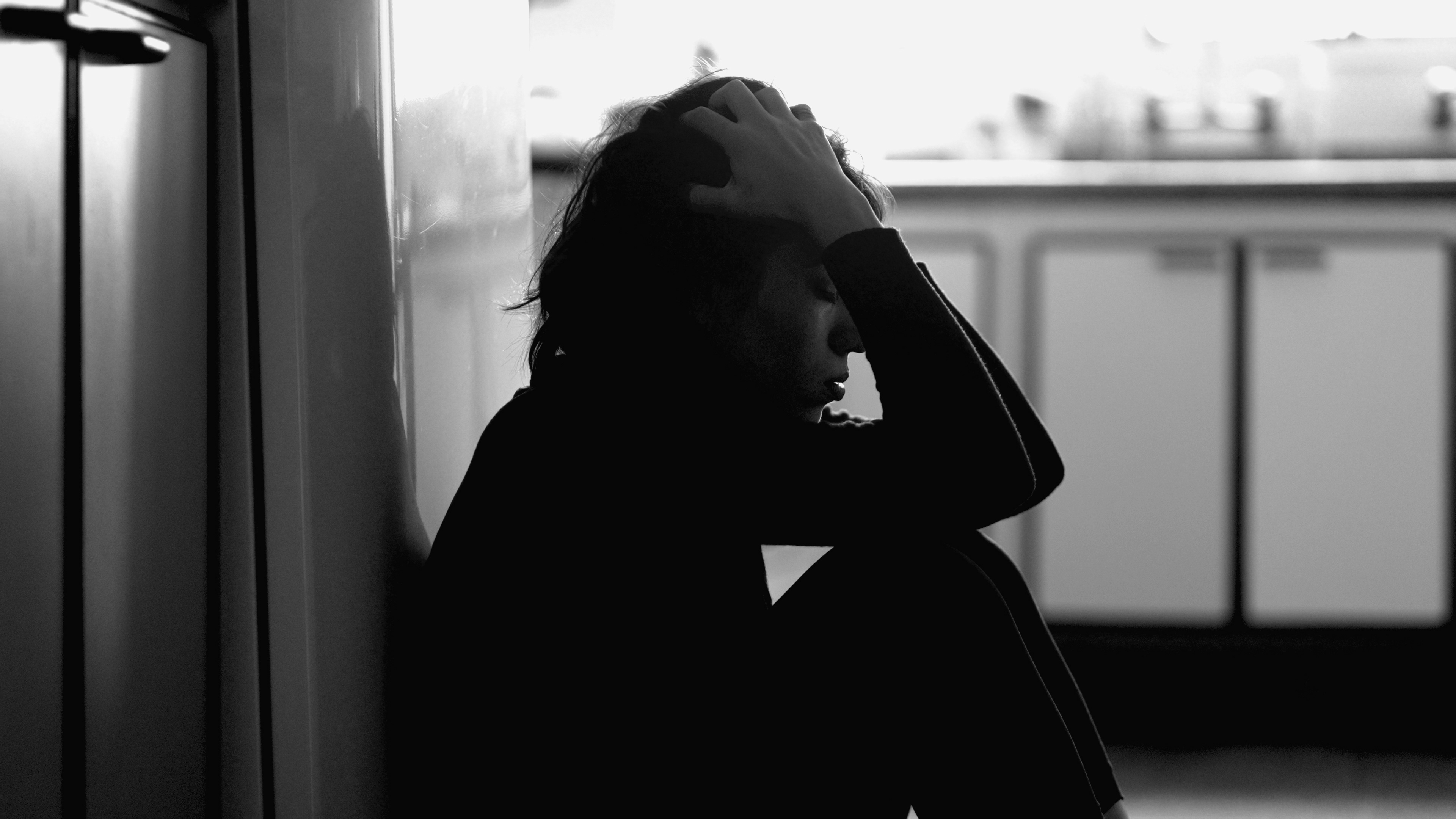 женщина сидит, держит голову, подавленная